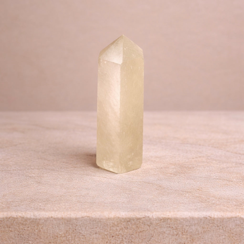 Boho Beth citrine crystal point standing upright on a soft beige marble surface, symbolising abundance, confidence and manifestation energy
