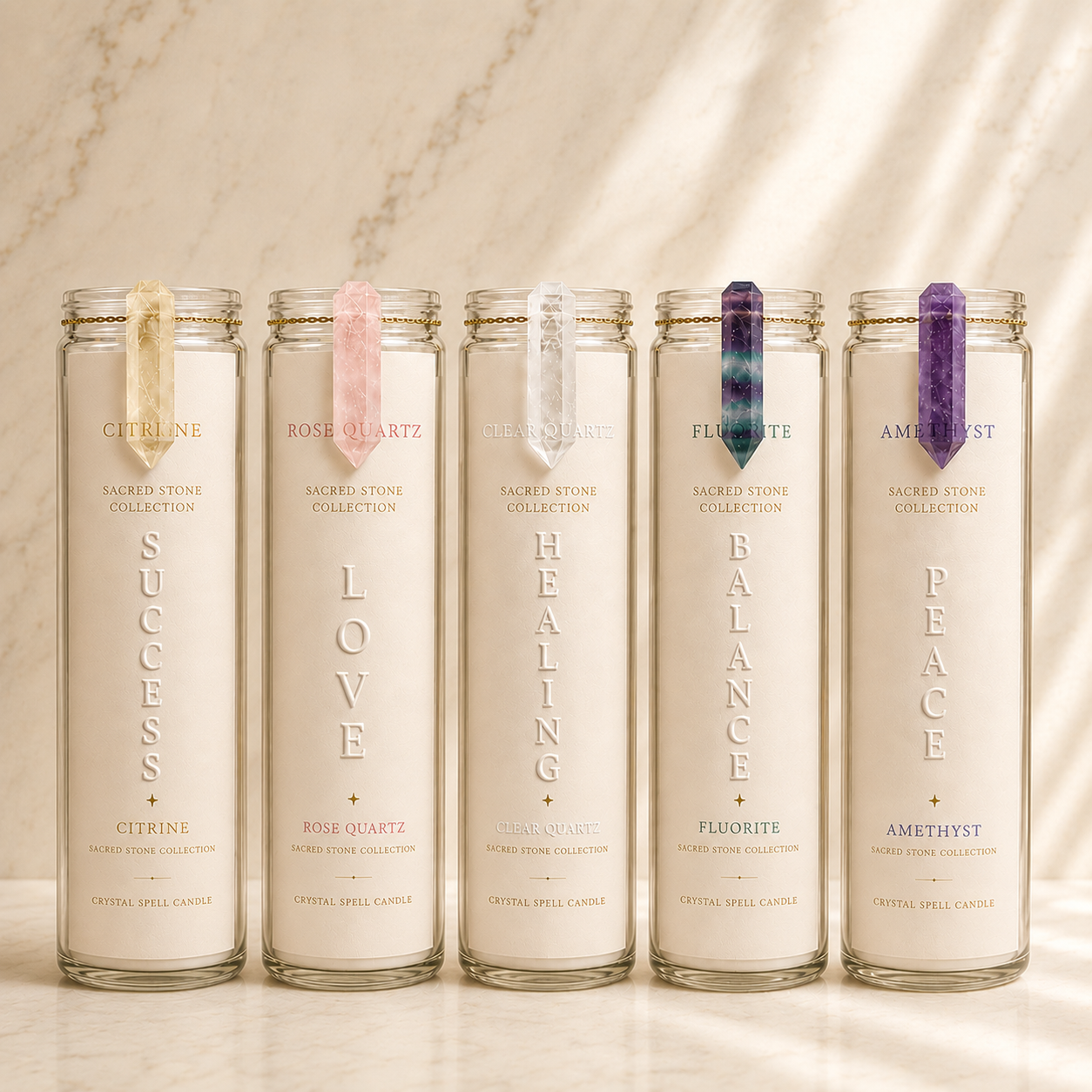 Five tall clear glass prayer candles with white wax are lined up on a light marble surface against a marble wall. Each candle has a different colored ribbon bookmark and is labeled with a sacred stone name: Citrine, Rose Quartz, Lapis Lazuli, Fluorite, and Amethyst.