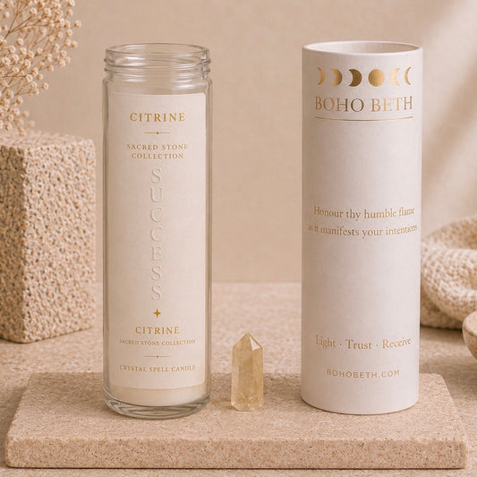 A glass jar candle labeled Citrine from the Sacred Stone Collection by Boho Beth, shown next to its white cylindrical packaging tube on a beige stone surface with dried flowers and neutral decor in the background.