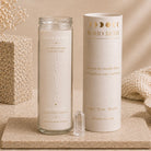 A clear glass jar candle labeled 'HEALING' from the BOHO BETH Sacred Stone Collection stands next to its matching cream-colored cylindrical packaging box on a stone surface, with a clear crystal pointed upward in front.