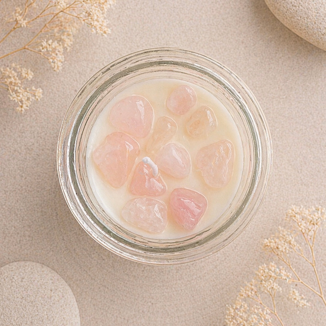 Glass jar with rose quartz crystal chips on a beige surface with dried flowers