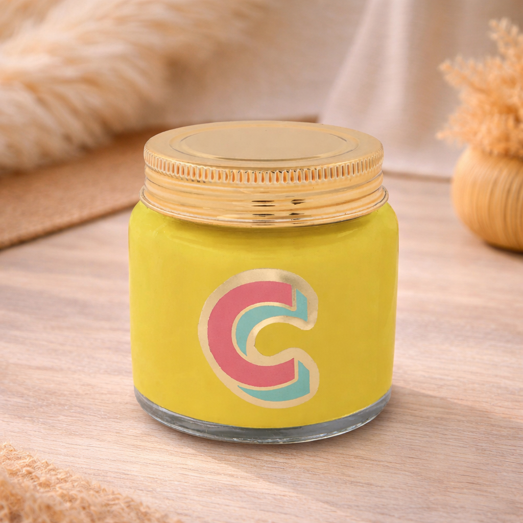 Personalised colour pop letter c candle jar with yellow wax and gold lid on bohemian background