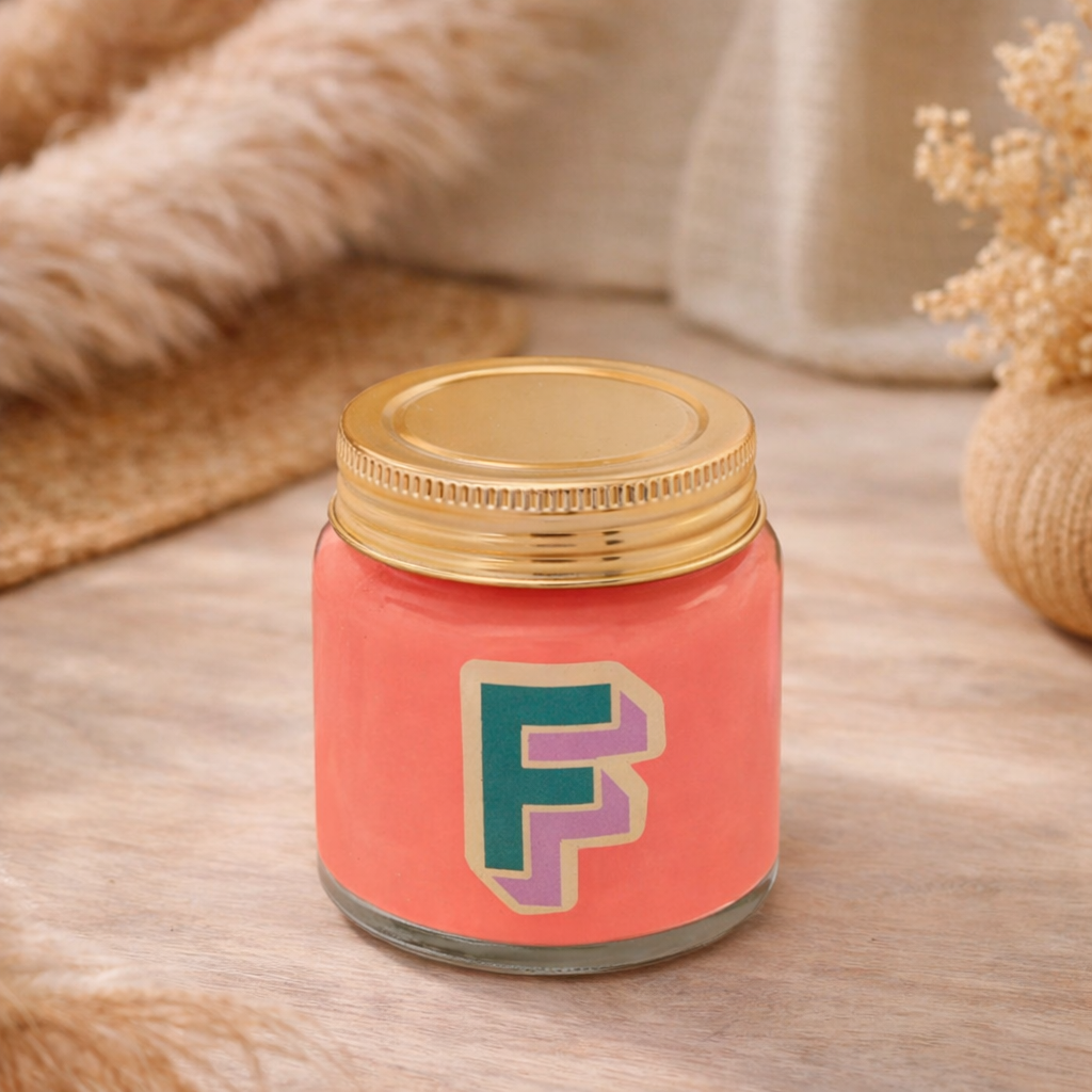 Personalised colour pop letter f candle jar with pastel wax and gold lid on bohemian background