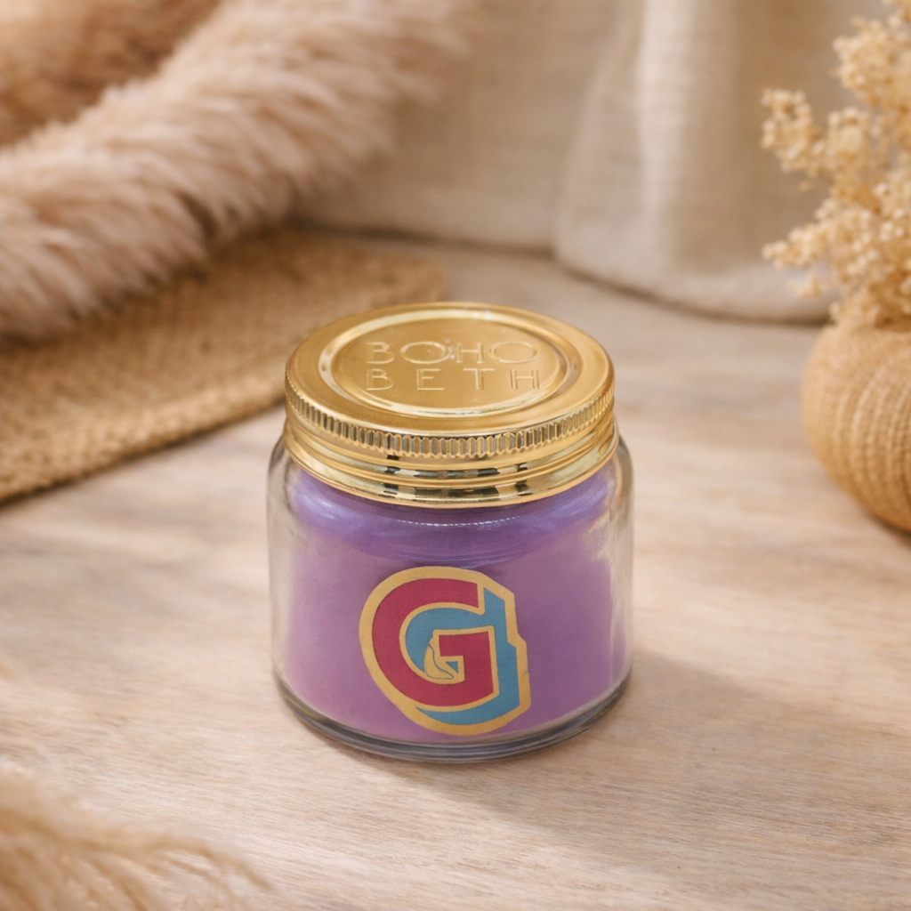 Personalised colour pop letter g candle jar with purple wax and gold lid on bohemian background